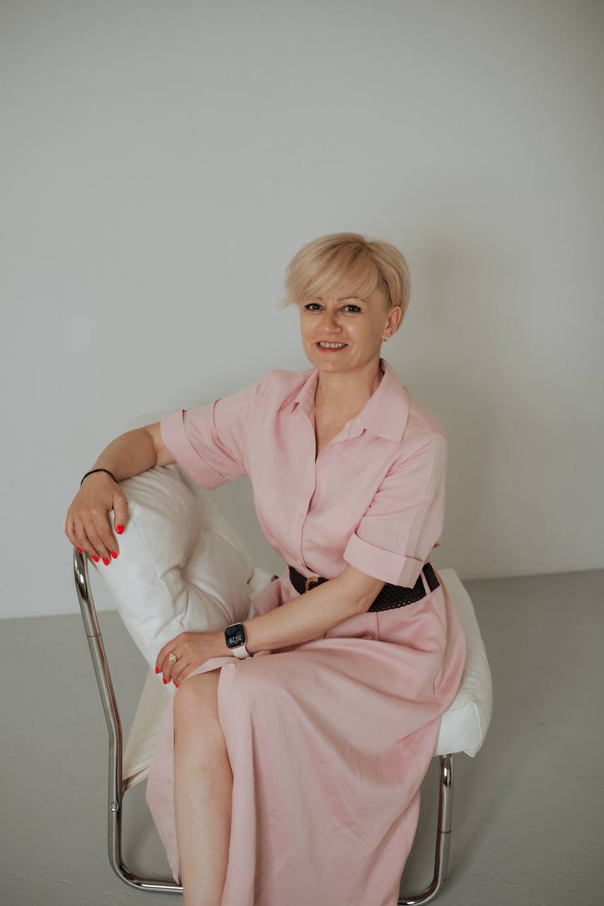 Міла у рожевій сукні, сидячи у світлій студії